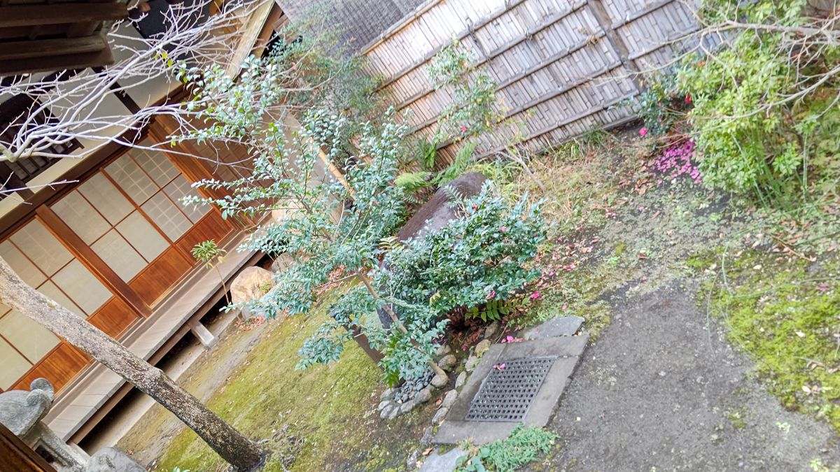上から見下ろした和館の中庭。苔と植え込み、石灯籠の向こうに障子の縁側