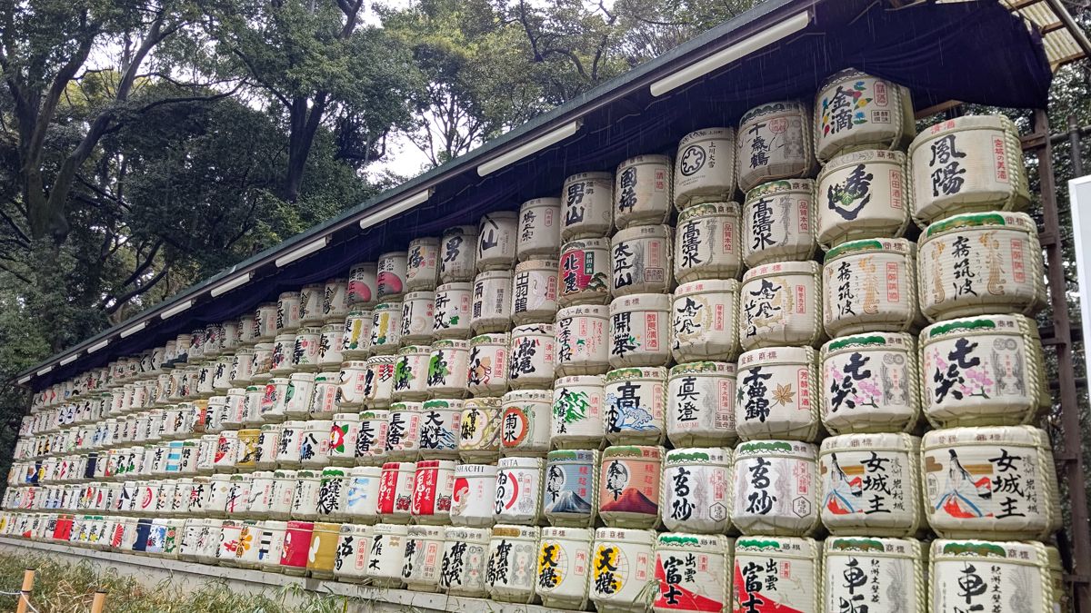 森を背に、銘柄の書かれた菰巻きの酒樽が何段にも積まれて並ぶ